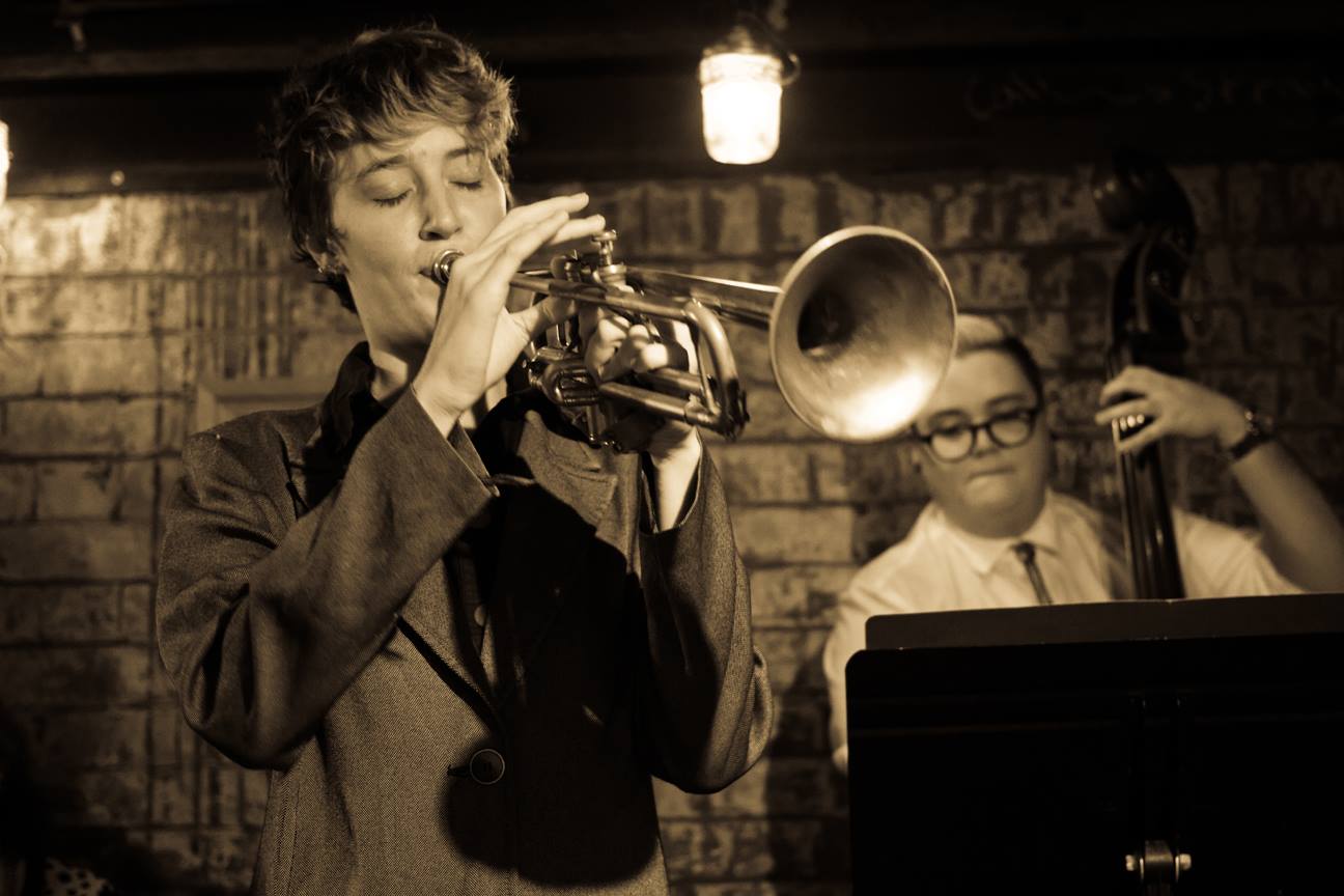 Alice plays trumpet in a bar. Sepia tone filter.