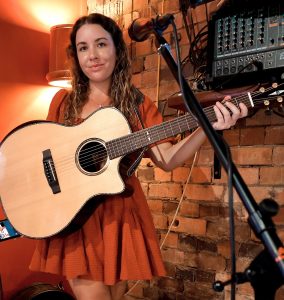 Kat Kellalea on stage with a guitar