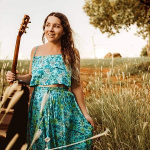 Kat Kellalea in a field with a guitar