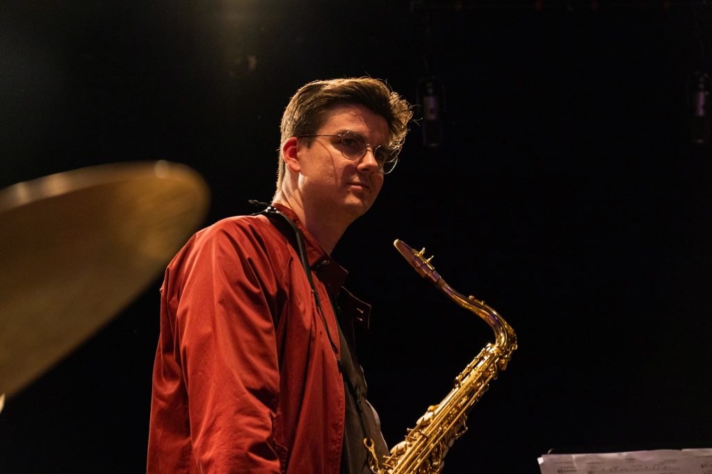 Isaac Power on stage with a saxophone