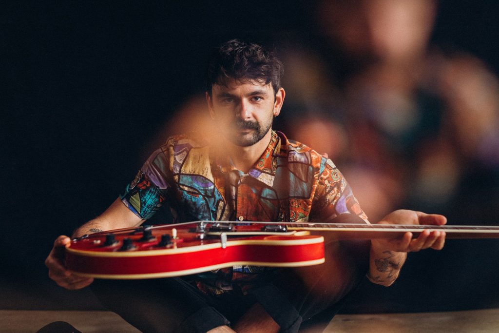 callum allardice holding a guitar on his lap